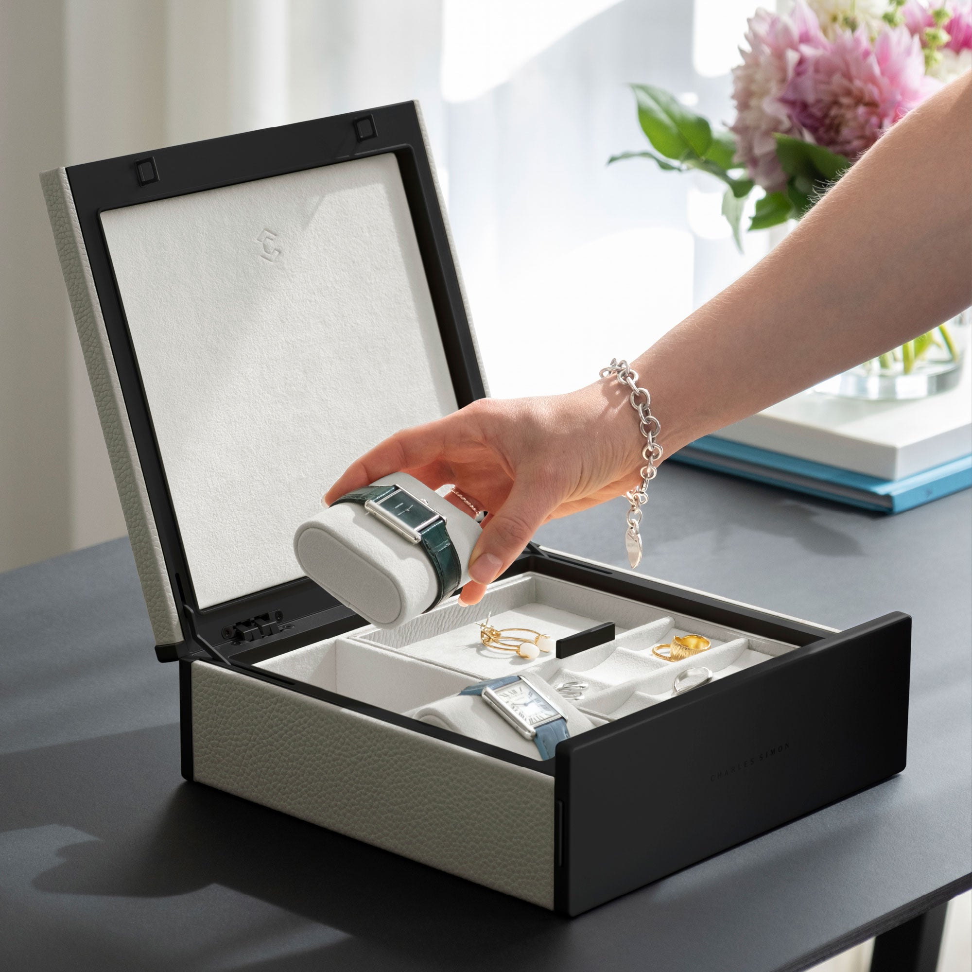 Lifestyle photo of Taylor 2 Watch and Jewelry box in white leather and alabaster interior. Woman is grabbing Cartier watch placed on alabaster watch cushion from the jewelry organizer. The luxury box is storing 2 watches in total as well as a collection of fine jewelry, including earrings and rings.
