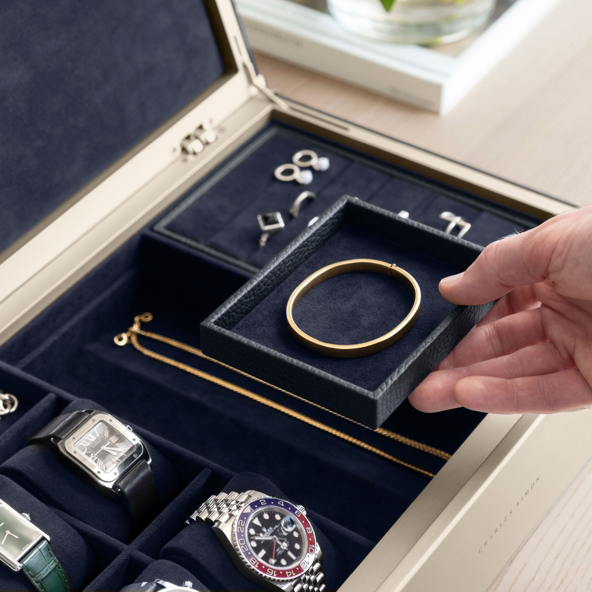 Detail photo of man taking gold necklace from the organization compartment of his gold Taylor 4 Watch and jewelry box in marine leather.