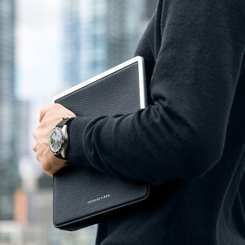 Lifestyle shot of man wearing luxury watch holding the Fraser travel wallet by Charles Simon